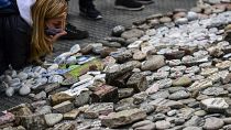 Egy nő megpuszilja elvesztett szerettének a nevével ellátott követ
