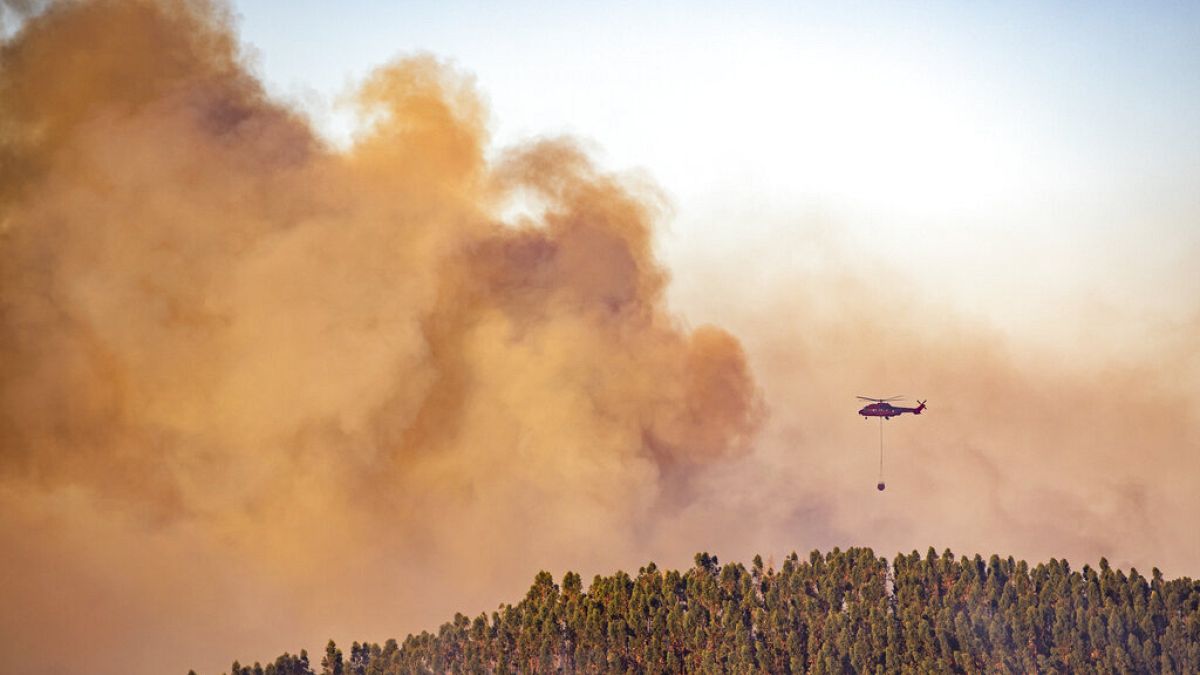 A helicopter works as a wildfire advances, in Spain