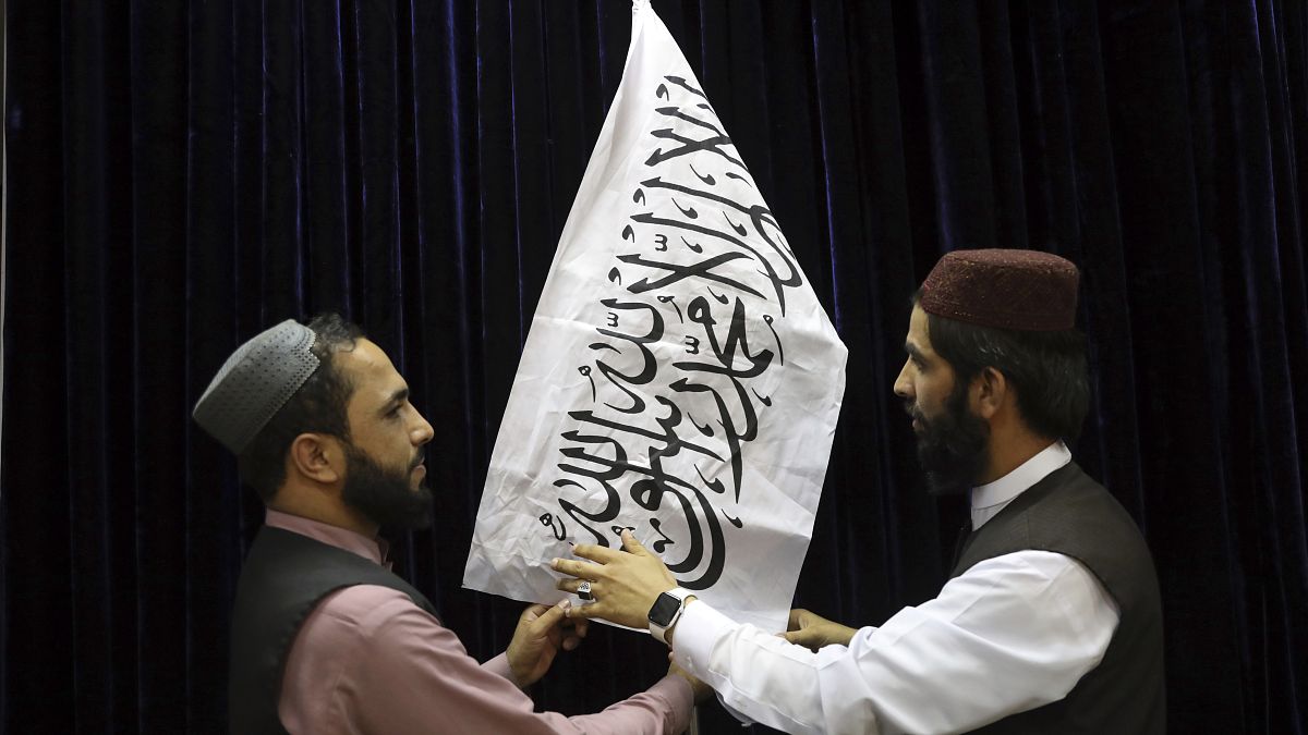 Oficiales talibanes arreglan la bandera blanca con la shahada, antes de la conferencia de prensa en Kabul, Afganistán, el 17 de agosto de 2021.