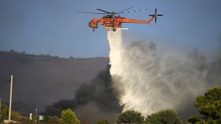 An helicopter drops water over a wildfire in Siderina village about 55 kilometers (34 miles) south of Athens, Greece, Monday, Aug. 16, 2021
