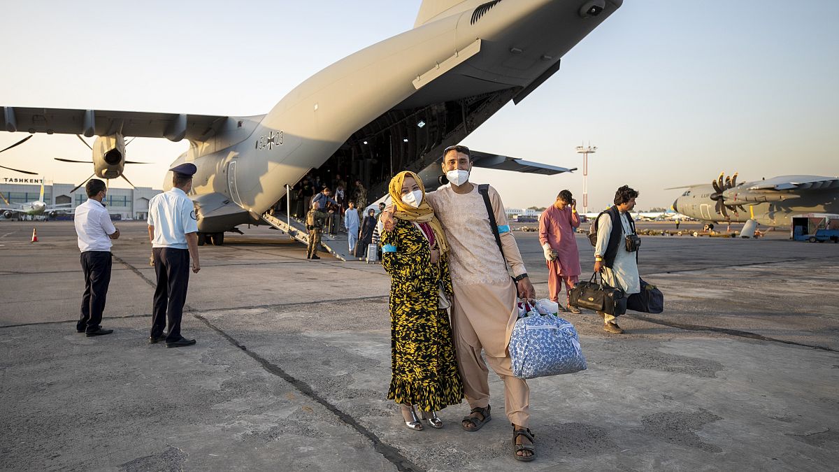 People evacuated from Afghanistan pose in front of a German Bundeswehr airplane after arriving at the airport in Tashkent, Uzbekistan, Aug. 17, 2021. 