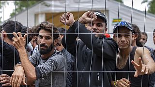 Migrants stand behind a fence inside the newly built refugee camp in the Rudninkai military training ground, some 38km (23,6 miles) south from Vilnius