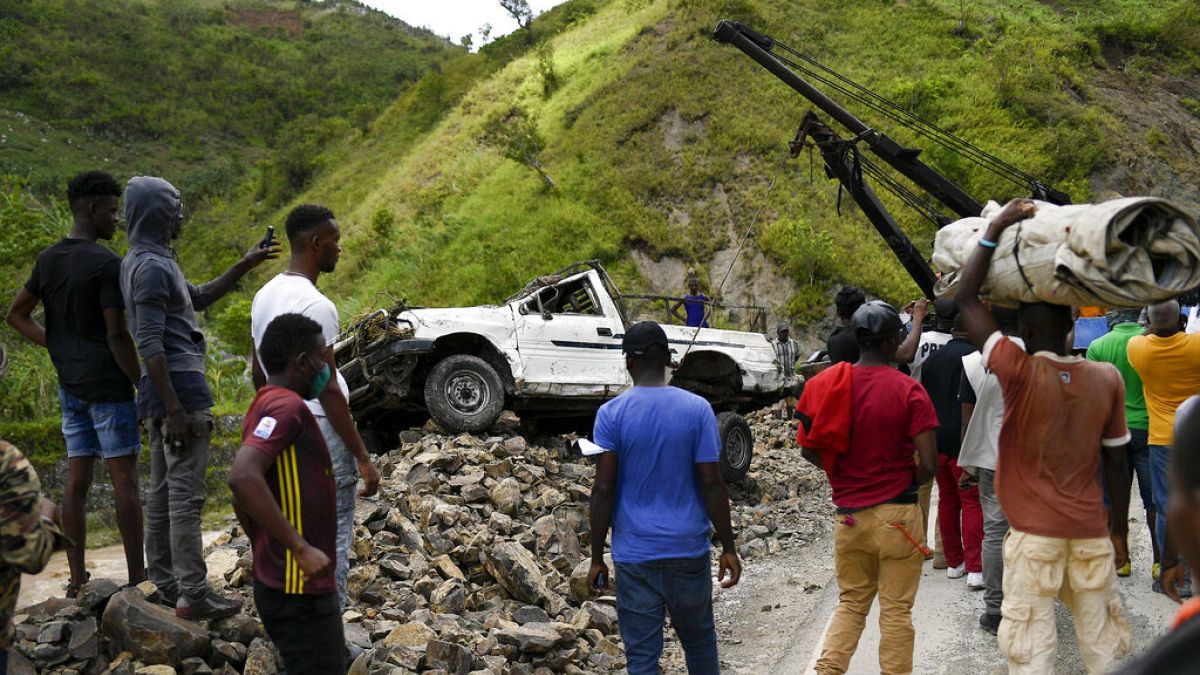 A crane removes a truck from a pile of rocks after landslides triggered by a 7.2-magnitude earthquake that hit four days prior in River Glass, Haiti, Wednesday, Aug. 18, 2021.