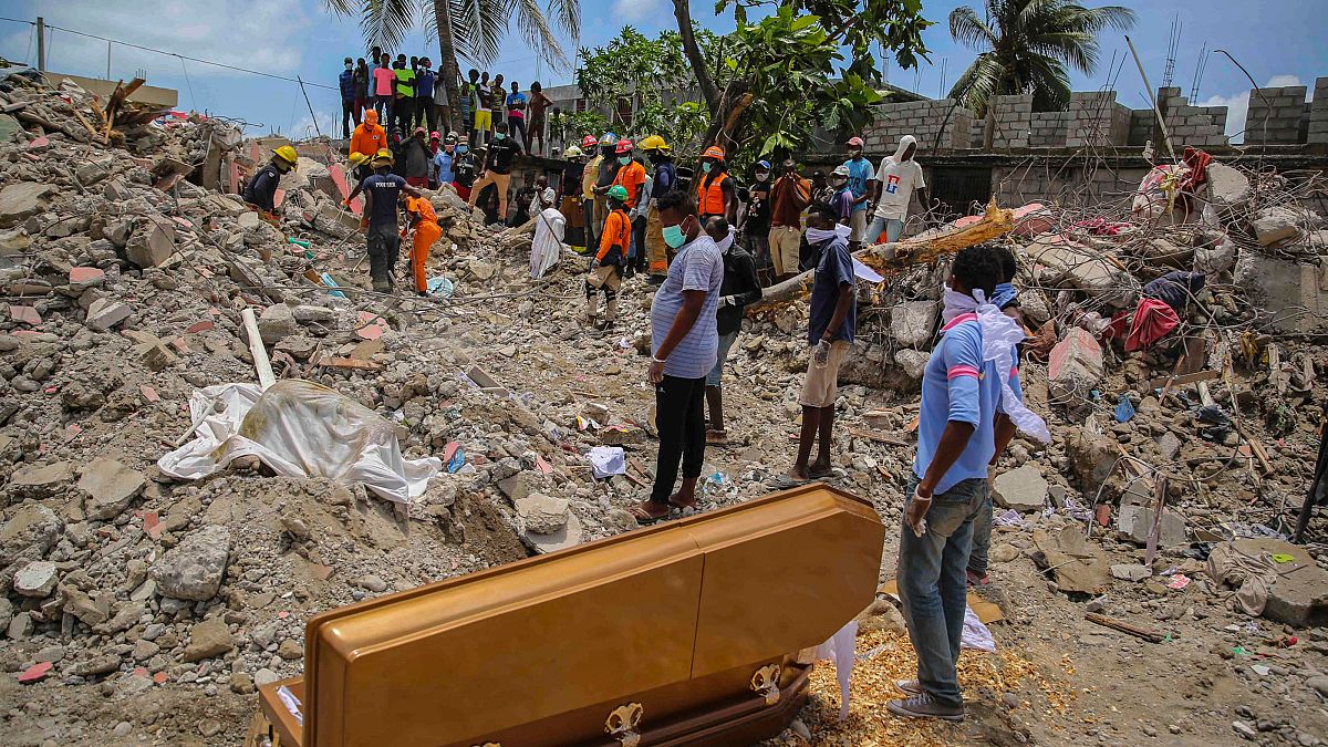 Emberek állnak a földrengés egyik halálos áldozatának a koporsója mellett, akinek holttestét a romok alatt találták meg