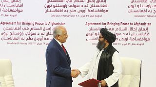 مبعوث السلام الأمريكي زلماي خليل زاد والملا عبد الغني بردار الزعيم السياسي الأعلى لحركة طالبان يتصافحان بعد توقيع اتفاق السلام في الدوحة، 29 فبراير 2020