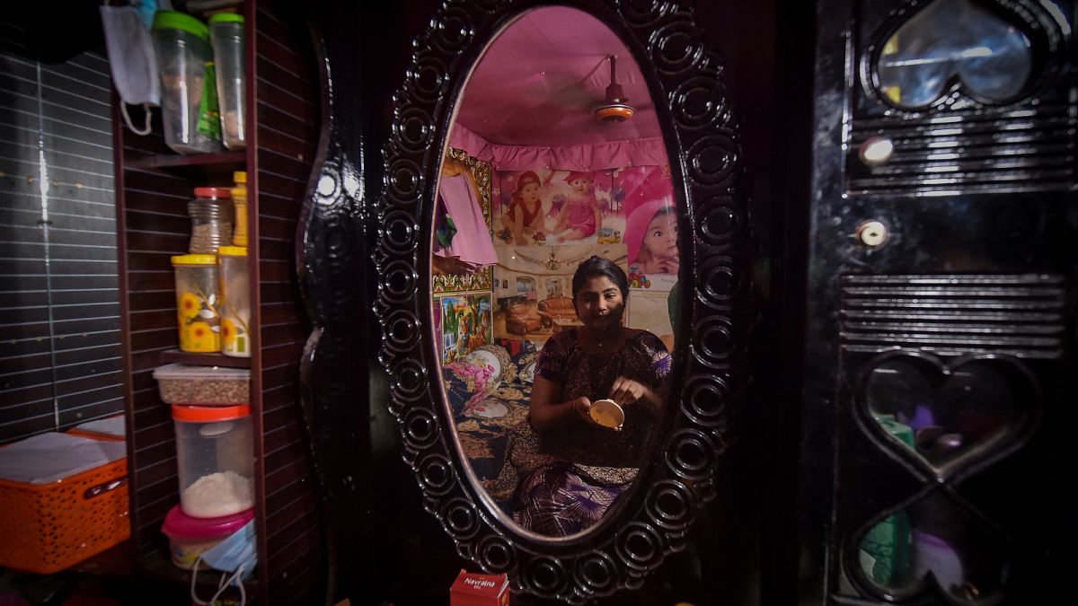 عاملة جنس تضع مساحيق التجميل أثناء جلوسها أمام مرآة في منزلها في دولاتديا في بنغلادش.