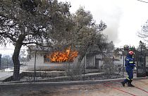 A firefighter extinguish the fire to a house during a wildfire in Thea area some 60 kilometers