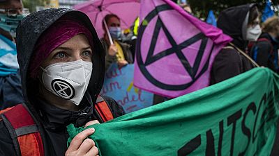 Demonstrators affiliated with global environmental movement Extinction Rebellion (XR), hold up banners.
