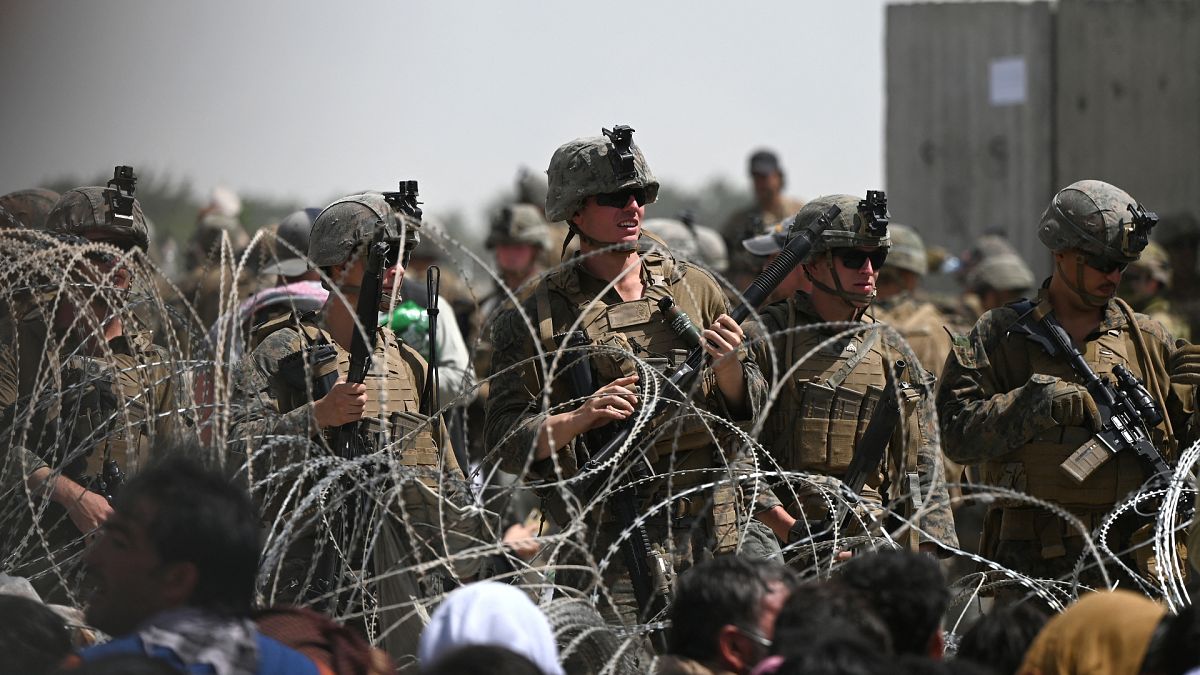 US soldiers stand guard behind barbed wire near Kabul airport, 20 August 2021