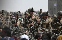 US soldiers stand guard behind barbed wire near Kabul airport, 20 August 2021