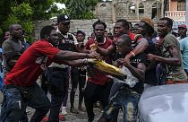 Gli uomini si azzuffano per un telo di plastica preso da un camion carico di aiuti umanitari nel quartiere di Viljoint a Les Cayes, Haiti