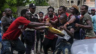 Gli uomini si azzuffano per un telo di plastica preso da un camion carico di aiuti umanitari nel quartiere di Viljoint a Les Cayes, Haiti