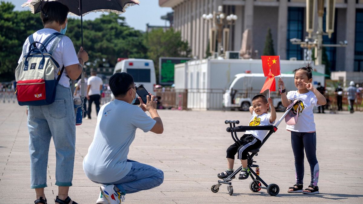 Children hold Chinese flags as they pose for a photo at Tiananmen Square in Beijing, on June 22, 2021. 