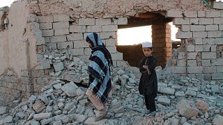 Afghan boys walk near a damaged house after airstrikes two weeks ago during a fight between government forces and the Taliban in Lashkar Gah.