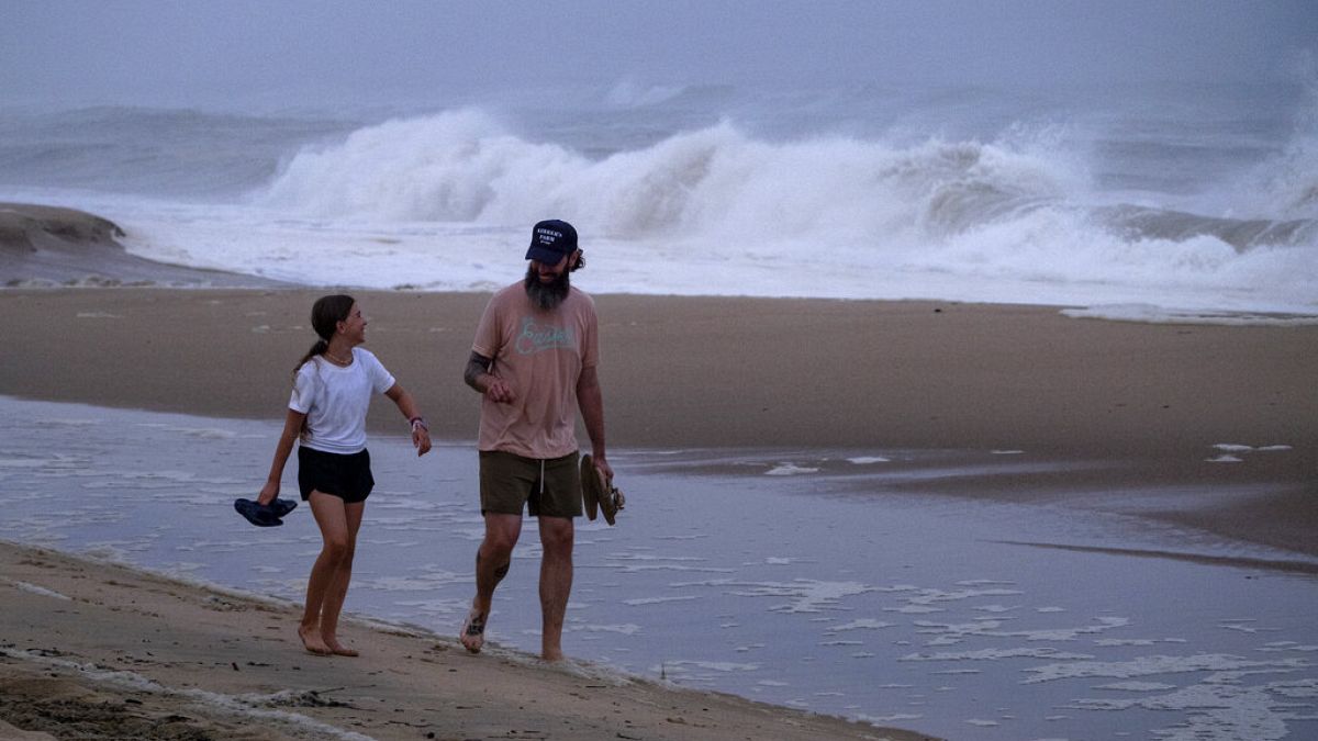 Promeneurs sur la plage de Montauk (Etat de New York, USA), devant une mer de plus en plus agitée à l'approche de l'ouragan "Henri", le 21/08/2021