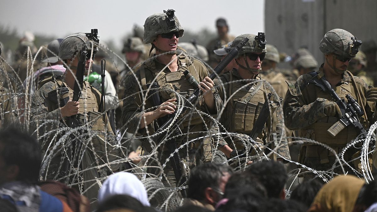 جنود أميركيون يقفون خلف أسلاك شائكة خلفها أفغان فروا لمطار كابول أملا في الخروج من أفغانستان بعد سيطرة طالبان على البلاد. 20/08/2021