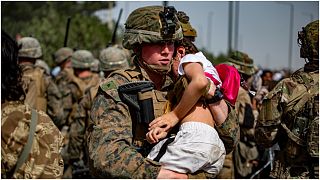 جندي أمريكي يحمل طفلة أفغانية بالقرب من المدخل الرئيس لمطار حامد كرزاي في كابول