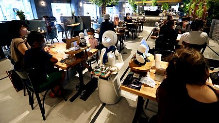 In this picture taken on August 17, 2021, a humanoid robot delivers drinks to customers at the Dawn Café in Tokyo.