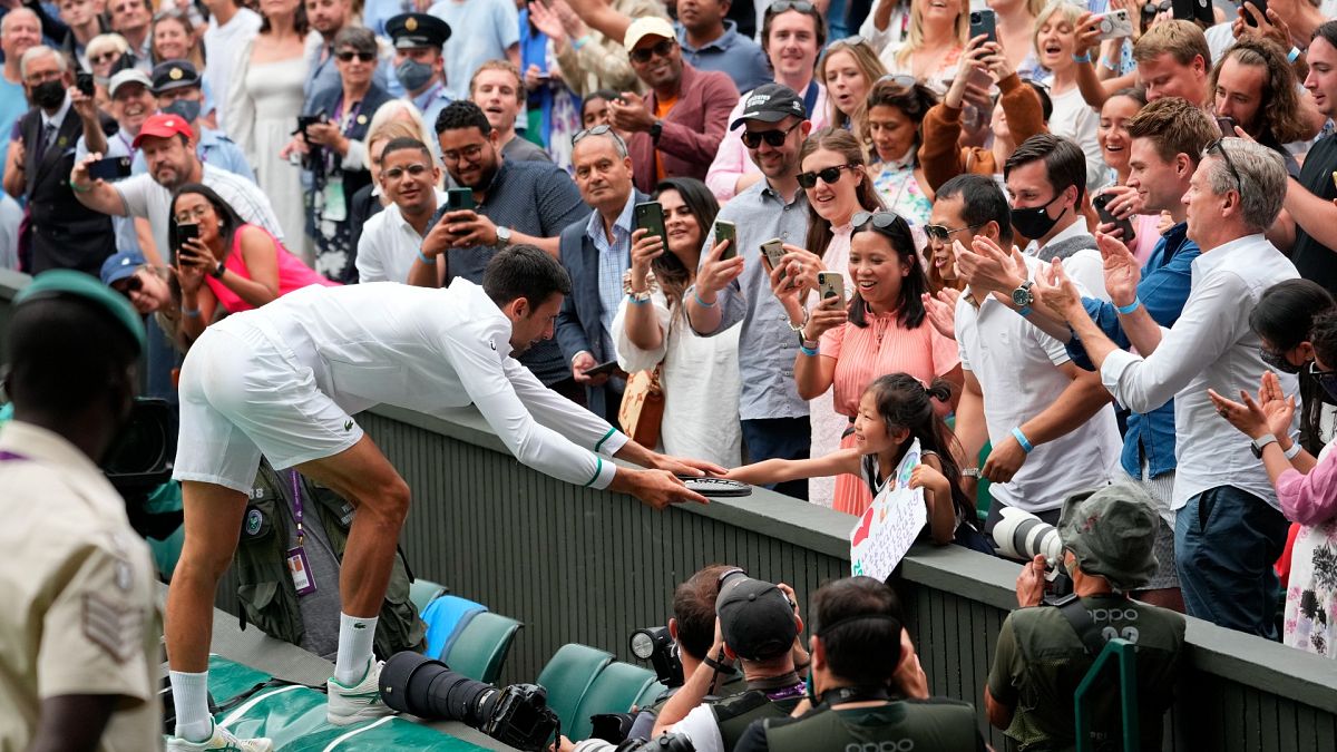 Serbia's Novak Djokovic presents his tennis racquet to a young fan after winning the men's singles final of the Wimbledon Tennis Championships in London, July 11, 2021.