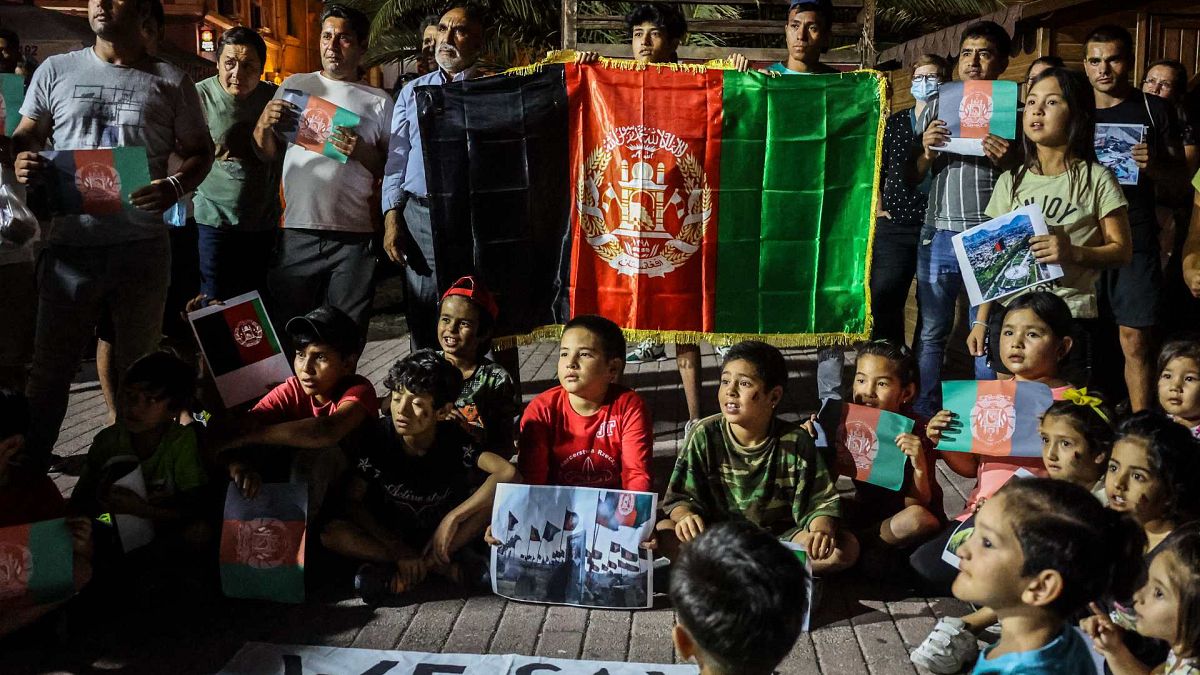 مهاجرون أفغان يحملون العلم الأفغاني أثناء احتجاجهم على سيطرة طالبان على أفغانستان، في جزيرة ليسبوس اليونانية، 16 أغسطس 2021