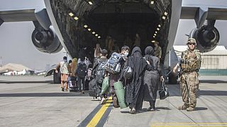 In this image provided by the US Marine Corps, families begin to board a US Air Force plane during an evacuation at Hamid Karzai International Airport, Kabul, August 23, 2021.