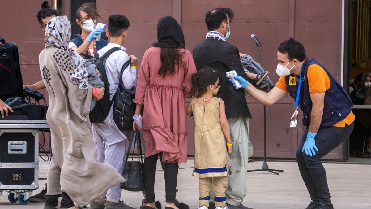 Varios sanitarios toman la temperatura a evacuados afganos a su llegada a Torrejón de Ardoz, en Madrid