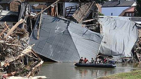 Military personnel on a boat on the Ahr river as the roof of a damaged house hangs on the water in Rech, western Germany, on July 21, 2021, after floods hit the region.