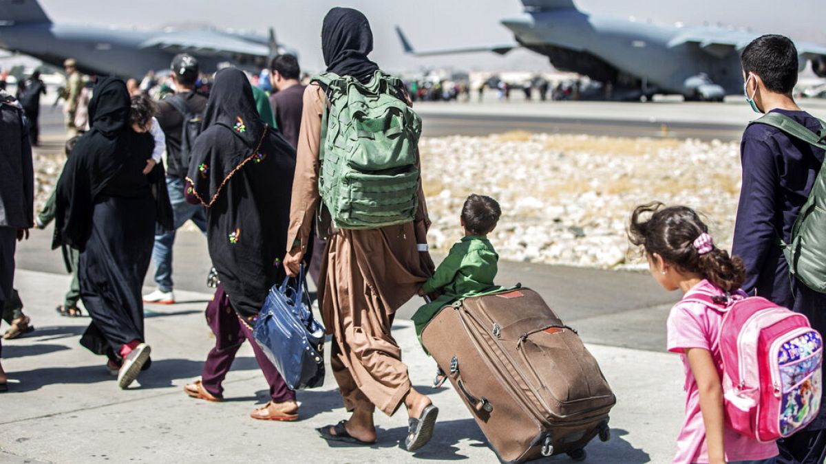 In this image provided by the U.S. Marine Corps, families walk towards their flight during ongoing evacuations at Hamid Karzai International Airport, Kabul,
