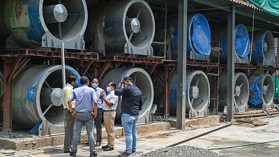Officials talk next to large fans at the construction site of a 25-metre (82 foot) high smog tower. Officials talk next to large fans at the construction site of a 25-metre (82 foot) high smog tower.