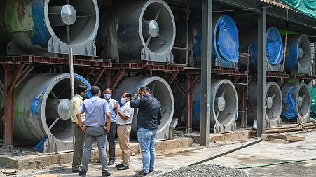Officials talk next to large fans at the construction site of a 25-metre (82 foot) high smog tower.