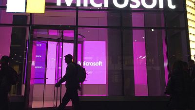 In this Nov. 10, 2016, file photo, people walk past a Microsoft office in New York.
