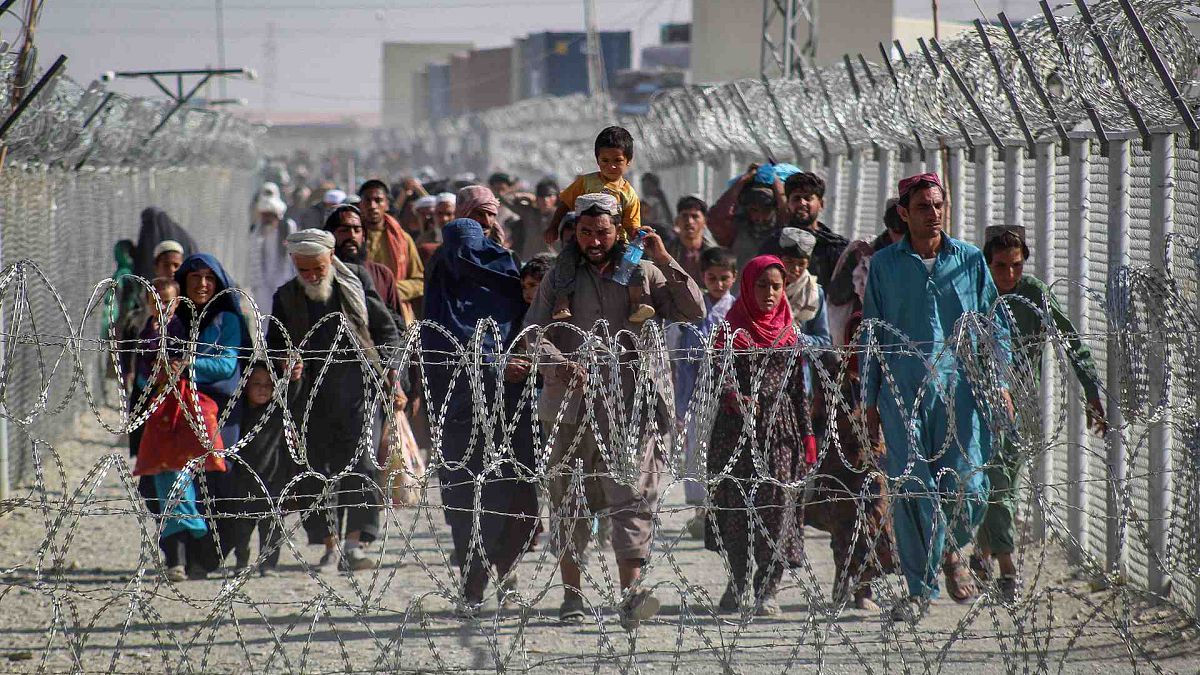 أفغان يسيرون على طول الأسوار عند وصولهم إلى باكستان عبر نقطة العبور الحدودية الباكستانية الأفغانية في شامان، 24 أغسطس 2021