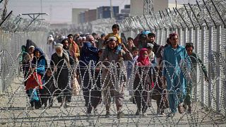 أفغان يسيرون على طول الأسوار عند وصولهم إلى باكستان عبر نقطة العبور الحدودية الباكستانية الأفغانية في شامان، 24 أغسطس 2021