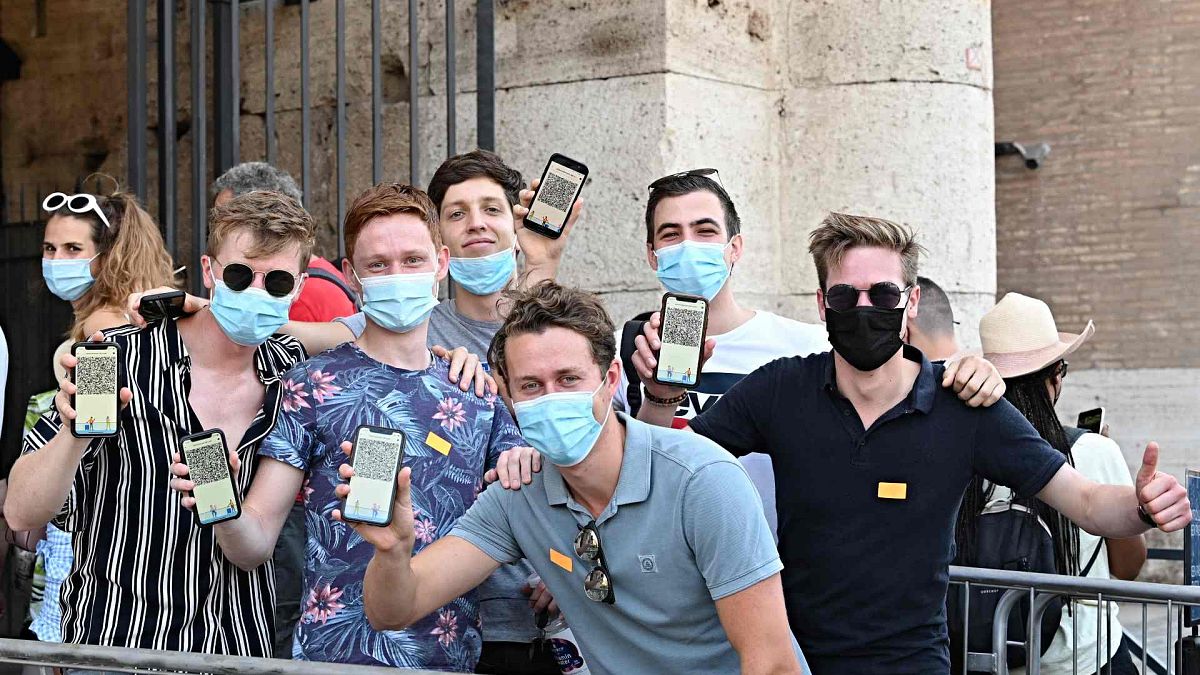 يُظهر الزائرون شهادات التطعيم ضد كوفيد-19 الخاصة بهم أثناء وقوفهم لالتقاط صورة فوتوغرافية قبل دخول الكولوسيوم القديم في وسط روما، إيطاليا، 6 أغسطس 2021