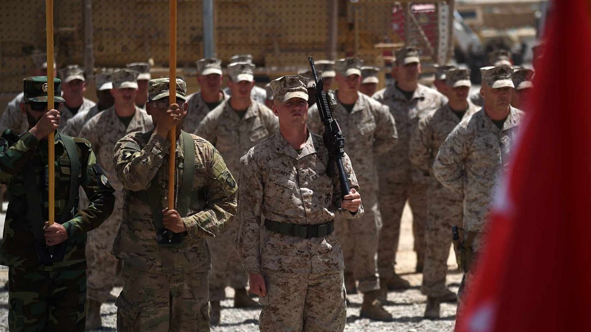 جنود من مشاة البحرية الأمريكية والجيش الوطني الأفغاني يحملون الأعلام خلال حفل تسليم في معسكر ليذرنيك في لاشكر جاه في ولاية هلمند الأفغانية، 29 أبريل 2017