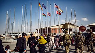 جنود أمريكيون يرافقون مجموعة من الأشخاص إلى صالة الوصول في مطار حامد كرزاي الدولي، يوم الاثنين 23 أغسطس، 2021.