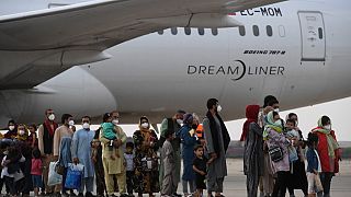Refugees queue on the tarmac after disembarking from an evacuation flight from Kabul, at the Torrejon de Ardoz air base, 30 km from Madrid, on August 24, 2021.