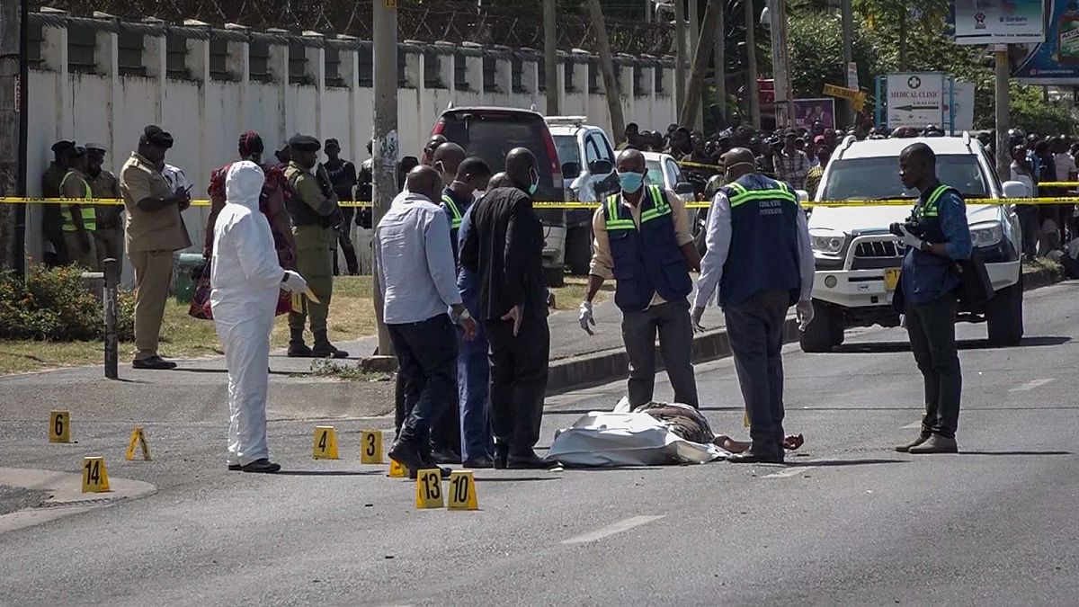 تقف قوات الأمن وخبراء الطب الشرعي بالقرب من جثة مغطاة جزئيًا في شارع بالقرب من السفارة الفرنسية في دار السلام، تنزانيا، الأربعاء 25 أغسطس 2021