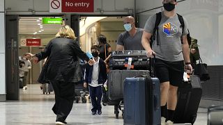 A woman runs to greet a child as passengers arrive at Terminal 5 of Heathrow Airport in London, Monday, Aug. 2, 2021.