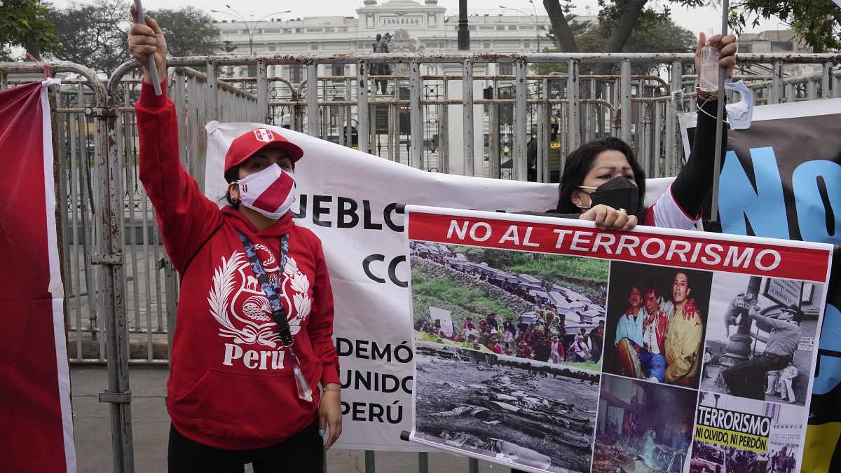Активистка держит плакат "Нет терроризму" у здания Конгресса Перу 26 августа 2021