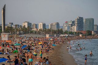 People enjoy the hot weather on a beach in Barcelona, Spain.