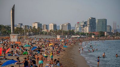 People enjoy the hot weather on a beach in Barcelona, Spain.