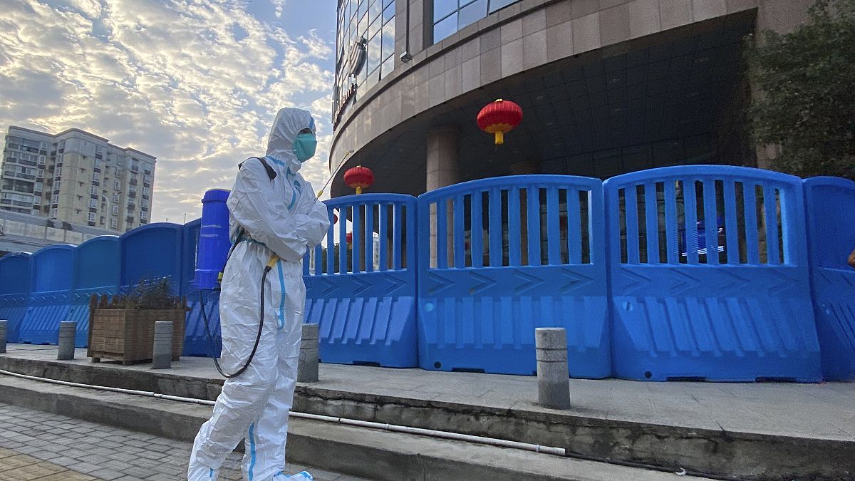In this Feb. 6, 2021, file a worker in protectively overalls and carrying disinfecting equipment walks outside the Wuhan Central Hospital.