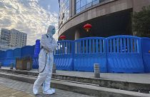 In this Feb. 6, 2021, file a worker in protectively overalls and carrying disinfecting equipment walks outside the Wuhan Central Hospital.