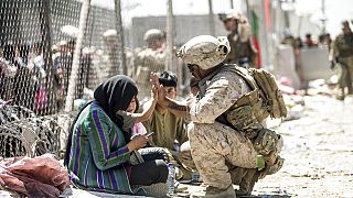 Un marine estadounidense choca la palma de su mano con un niño afgano en las inmediaciones del aeropuerto de Kabul