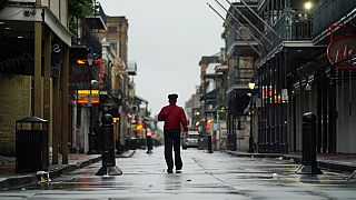 A man walks down a mostly deserted Bourbon Street in the French Quarter as the early effects of Hurricane Ida are felt, Sunday, Aug. 29, 2021, in New Orleans, La.