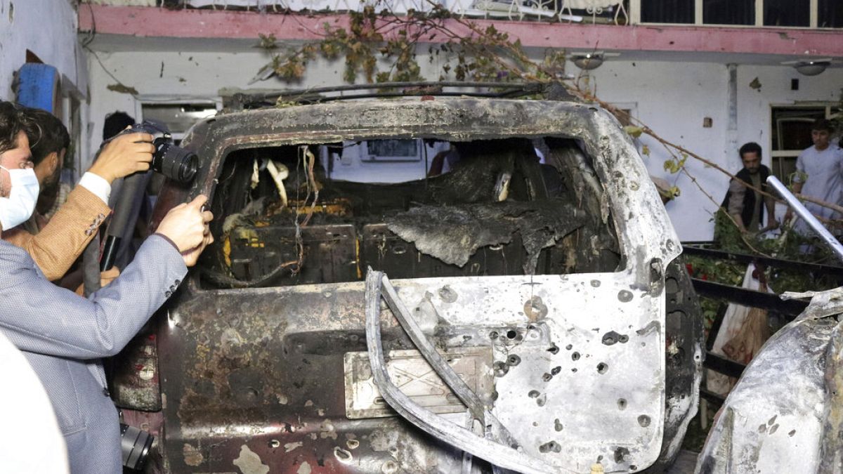 Des journalistes afghans prennent en photo un véhicule détruit à Kaboul le 29 août 2021