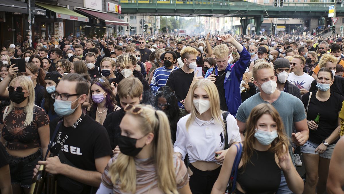 People, most of them wearing masks, dance behind a truck as they attend a demonstration named 'Train of Love' in Berlin, Germany, Saturday, Aug. 28, 2021