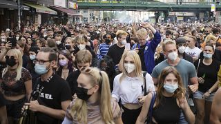 People, most of them wearing masks, dance behind a truck as they attend a demonstration named 'Train of Love' in Berlin, Germany, Saturday, Aug. 28, 2021