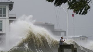A man takes pictures of high waves along the shore of Lake Pontchartrain as Hurricane Ida nears, Aug. 29, 2021, in New Orleans.